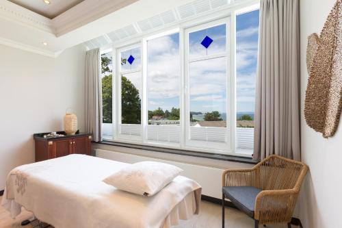 奥斯特巴德·哥伦Vju Hotel Rügen的一间卧室配有一张床、一把椅子和窗户。