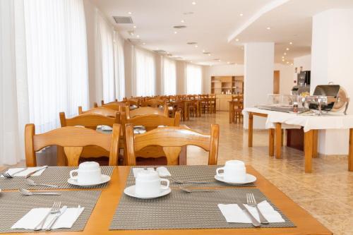 阿姆泼斯塔Hotel Montsia的一间带木桌和椅子的餐厅以及一间售货员