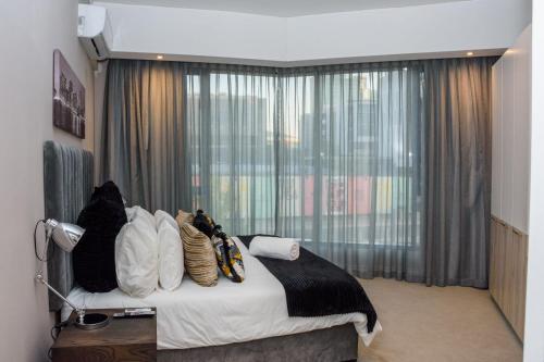 比勒陀利亚The Menlyn Main Residents Trilogy的卧室配有带枕头的床铺和窗户。