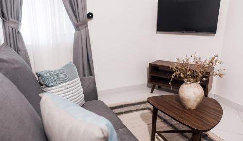 拉各斯Sigma Base Apartments的客厅配有沙发和桌子上的花瓶