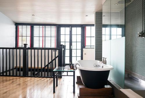 亨利昂泰晤士亨利杜文酒店的带浴缸和玻璃桌的浴室