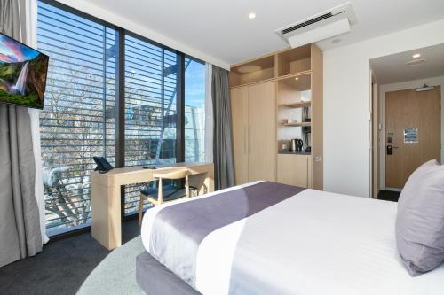 基督城Christchurch City Hotel的一间卧室配有一张床、一张书桌和一个大窗户
