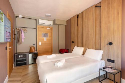 热那亚B&B Hotel Genova City Center的卧室配有一张白色的大床和一张桌子
