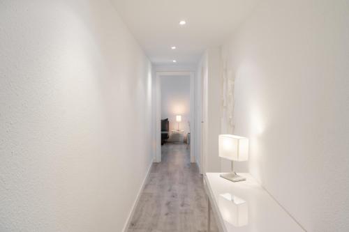萨拉戈萨Apartamento al lado de la Romareda的白色墙壁上的白色走廊,配有灯