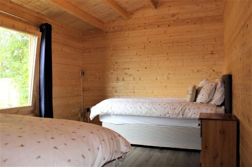 伊夫舍姆Stunning 5-Bed Cabin in Ashton Under Hill的木间设有两张床,设有窗户