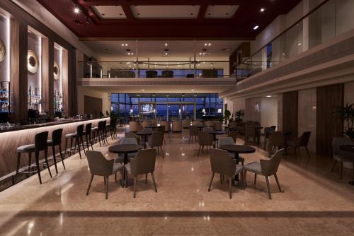 斯塔罗斯Atlantica Kalliston Resort - Adults Only的一间带桌椅的餐厅和一间酒吧