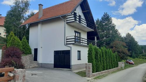 兹拉蒂博尔Kuća sa pogledom na Tornik的白色的房子,有黑色的大门和车道