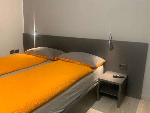 加尔达湖滨Rivacentro 2的一张带橙色床单和边桌的床