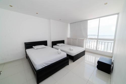 卡塔赫纳Cozy Apartment in El Laguito的白色客房的两张床,设有大窗户