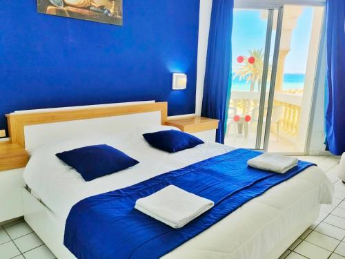 莫纳斯提尔Hotel Neptunia Skanes的蓝色的卧室设有一张带蓝色床单的床和一扇窗户