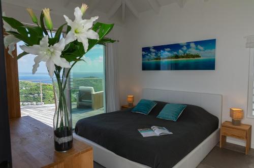 古斯塔维亚Villa La Vue - Vue panoramique sur les lagons的一间卧室,配有一张带白色花瓶的床
