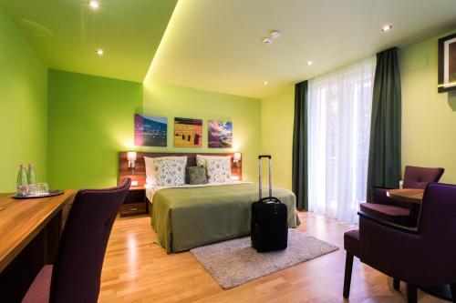 鲍洛通维拉戈什Tópart Hotel的一间卧室配有一张床、一张桌子和一张带行李箱的桌子