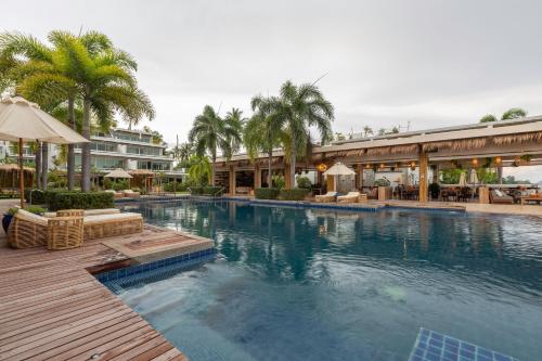 拉威海滩Selina Serenity Rawai Phuket的度假村内的大型游泳池配有椅子和遮阳伞