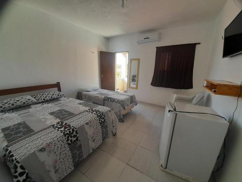 巴纳伊巴Pousada Progresso的客房设有两张床和一台冰箱。