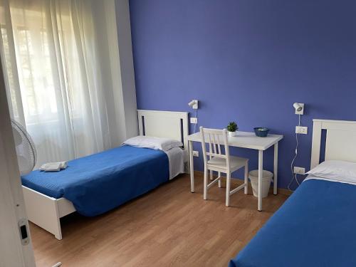 斯特雷萨Villa Vittoria的客房设有两张床、一张桌子和蓝色的墙壁