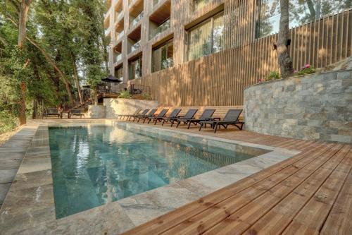 金沙Umani Hotel - Free Beach - Free Parking的一座带椅子的游泳池,位于大楼旁