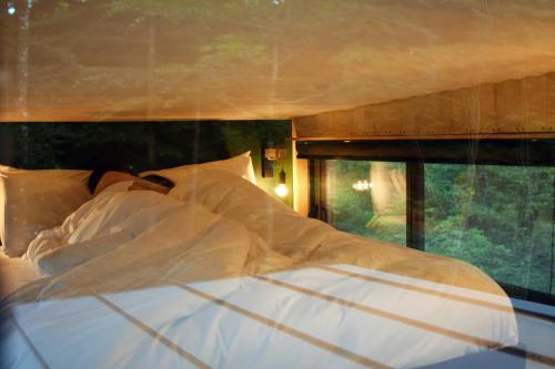Saint-LaurentInspire Tiny的一张带白色床单和枕头的床,靠窗