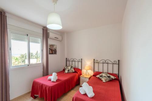 托罗克斯科斯塔Apartamento Coral的卧室内的两张床,配有红色床单