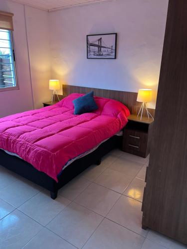 派桑杜Apart Del Este 1的一张红色的大床,位于带两盏灯的房间