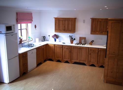 波弗特Beaufort House的厨房配有木制橱柜和白色冰箱。