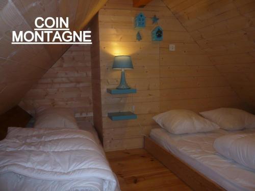 巴里吉斯APPARTEMENT CLAIR ET MODERNE AU CALME的小木屋卧室内的两张床,配有灯
