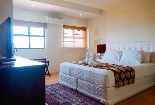 San Jose de BuenavistaRedDoorz @ Joyce Palace Antique的卧室配有一张白色大床和电视。