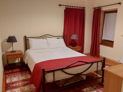 奥吉欧司吉玛洛斯Traditional Guesthouse Vrigiis的一间卧室配有一张带红色窗帘的大床