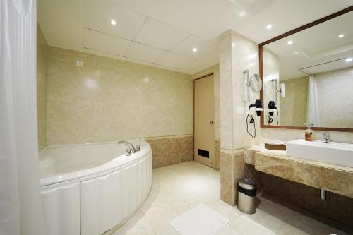 库姆巴科纳姆维哈品质酒店的浴室配有大浴缸、水槽和浴缸。