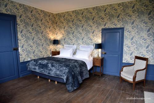 SanxayDomaine de la Briouse的一间卧室配有一张蓝色墙壁的床和一把椅子