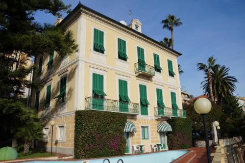 因佩里亚米拉马雷酒店的一座带绿色百叶窗的建筑和一座前方的游泳池