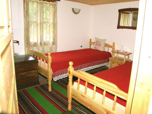 YakovtsiВила Любима的一间卧室设有两张木制床和红色毯子