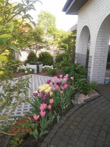 OstercappelnBoarding-Haus, Ostercappeln的砖砌走道上种着粉红色和黄色花的花园