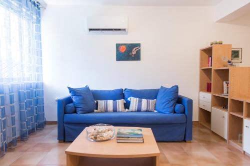 加拉塔斯AGIAZI Poros Summer House的客厅配有一张蓝色的沙发,配有一张桌子