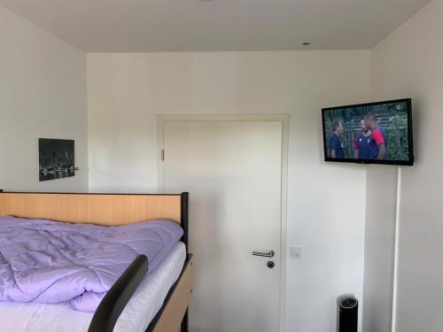 科隆FeWo Hostel的卧室配有一张床,墙上配有电视。