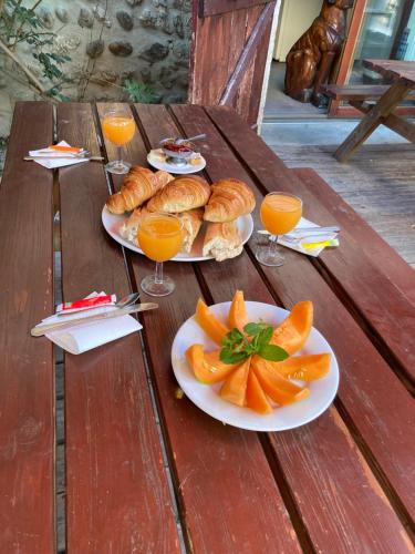 佩鲁日Chambres d hotes THE RESID的一张木桌,上面放有食物和橙汁