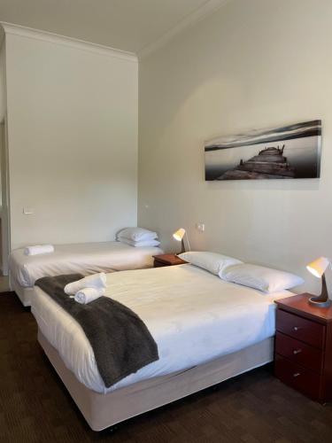 KanyapellaFalcon Hotel Motel的卧室内的两张床,配有两盏灯和一张墙上的照片