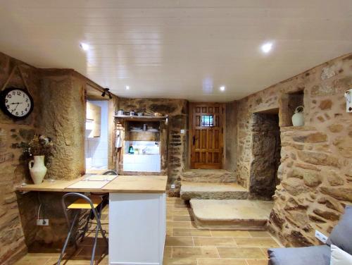 MazaricosA Cuadriña的厨房设有石墙和带时钟的柜台。