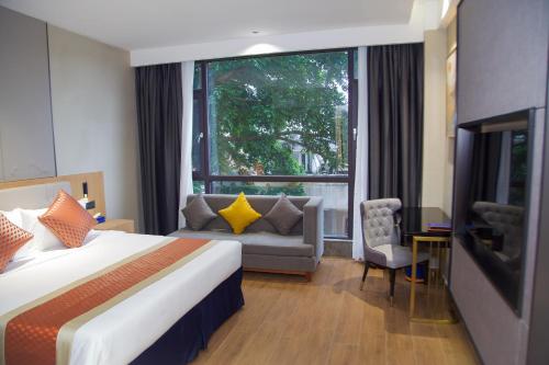 阿比让Hôtel FAMILLE MONDIALE的酒店客房设有床、沙发和窗户。