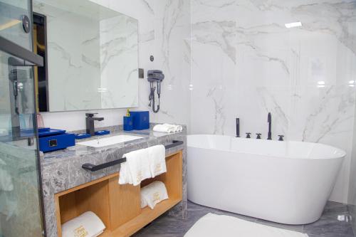 阿比让Hôtel FAMILLE MONDIALE的一间带大浴缸和大镜子的浴室