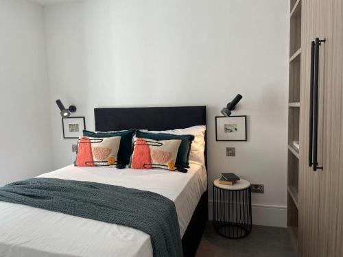 伦敦Brand new 3-bedroom home in London的一间卧室配有带橙色和绿色枕头的床