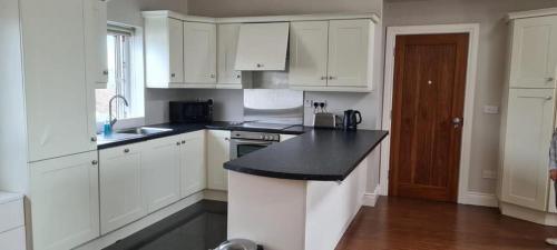 卡拉罗Carraroe Apartment 2的厨房配有白色橱柜和黑色台面