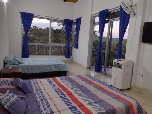 阿纳波伊马FINCA LA AMISTAD的一间卧室设有两张床,窗户配有蓝色窗帘