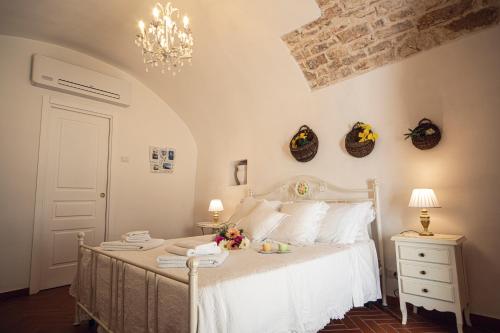 滨海波利尼亚诺Masseria Del Crocifisso的卧室配有白色的床和吊灯。