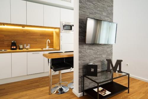 马拉加Minimal Rooms by ELE Apartments的厨房配有白色橱柜和酒吧凳