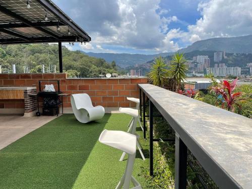 麦德林Housinn co-living Fatima en Medellín的阳台配有两把白色椅子和草