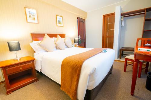 瓦拉斯El Tumi Hotel的酒店客房设有一张大床和一张书桌。
