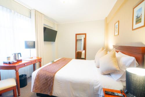 瓦拉斯El Tumi Hotel的配有一张床、一张书桌和一扇窗户的酒店客房