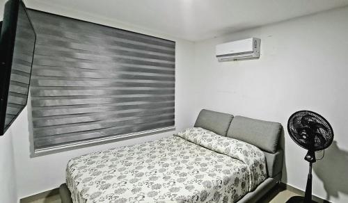巴兰基亚Espectacular Penthouse dúplex bien equipado的一间卧室配有一张床和一个带风扇的窗户。