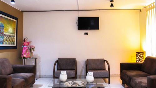 特鲁希略Hotel Chimu的客厅配有两把椅子和墙上的电视