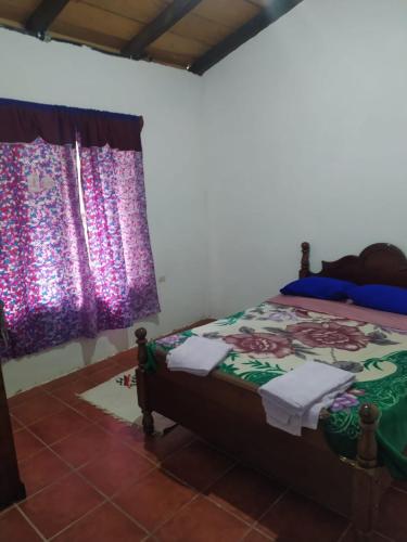 Hostal El Calvario del Bosque, Aldea Las Cruces, Cobán的一间卧室配有一张床和一个带紫色窗帘的窗户